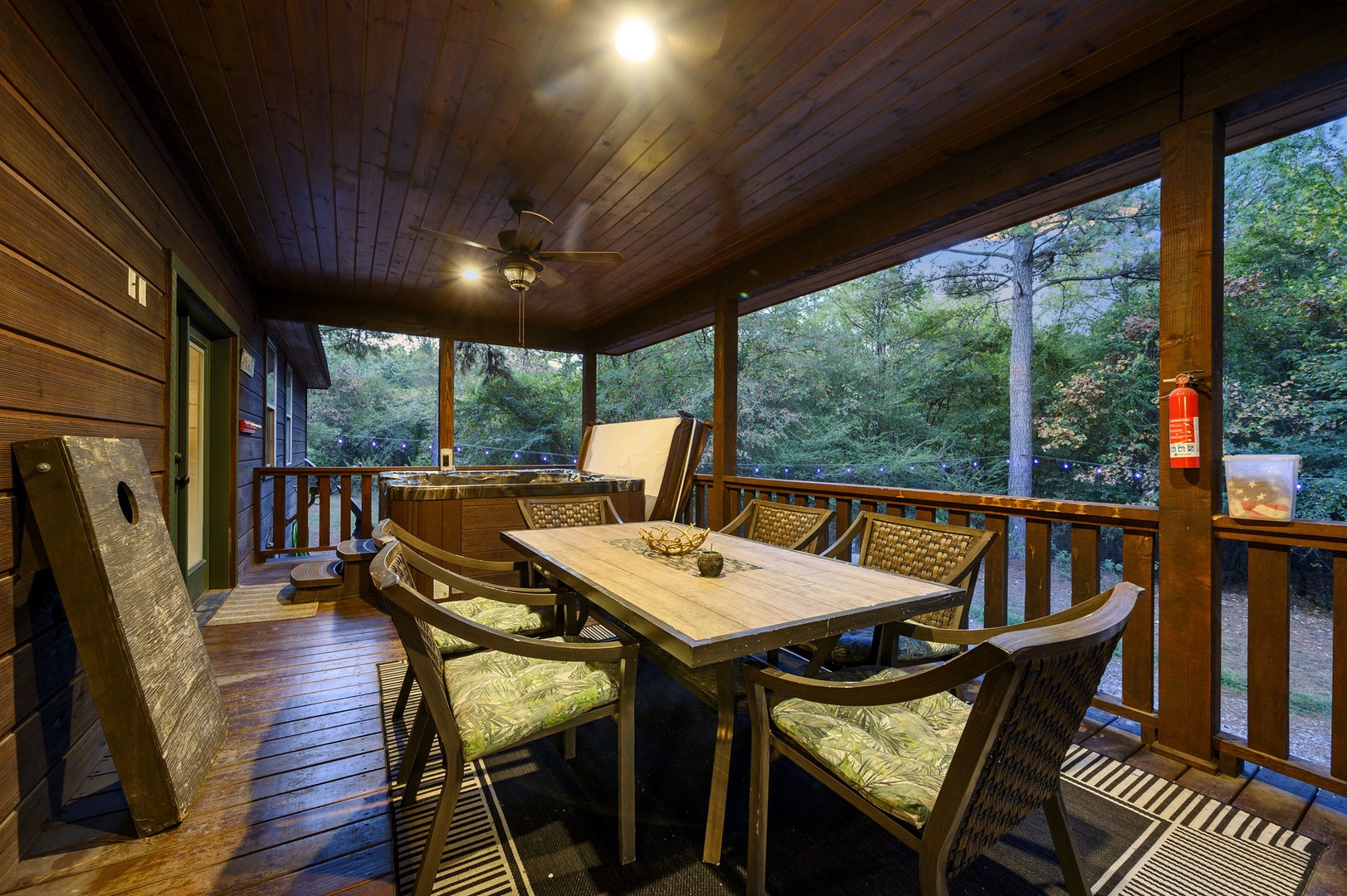 Your screened porch welcomes you with warm wood tones, inviting seating for six, and a peaceful view of the surrounding trees—perfect for morning coffee or evening meals.