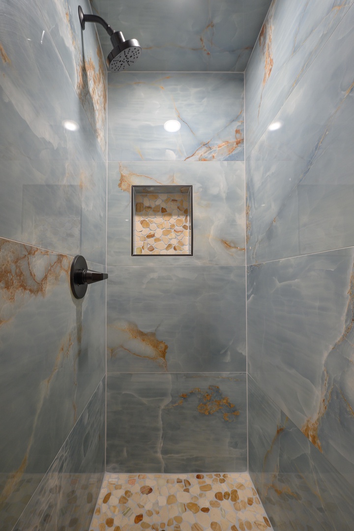 Step into your private sanctuary with elegant marble-style tiles, modern fixtures, and a built-in niche for your essentials.