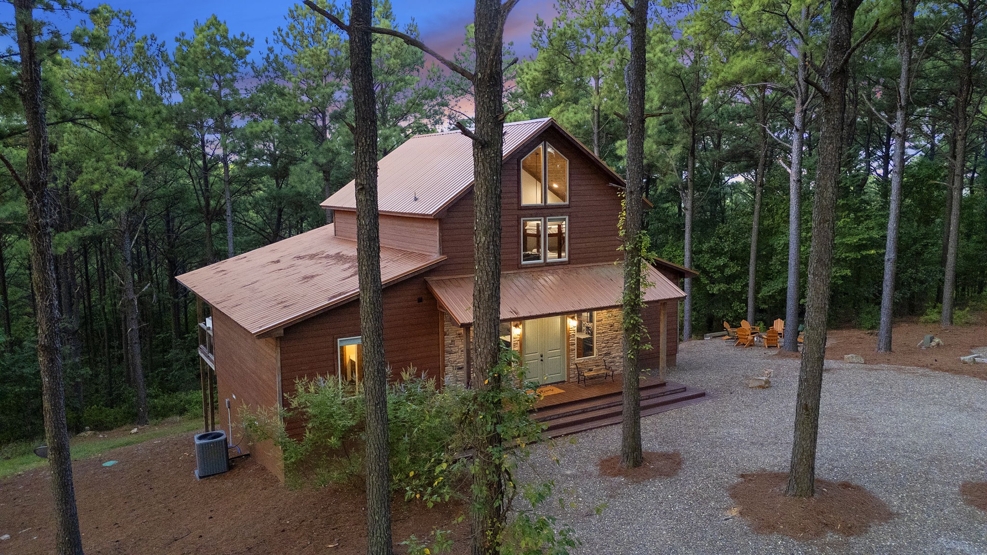 Nestled among towering pines, this charming cabin offers a peaceful forest retreat with warm lighting welcoming you at twilight.