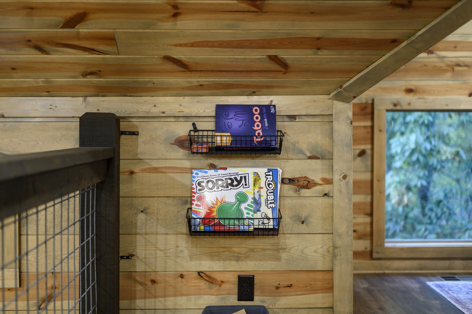 Board games await your next cozy evening, stored neatly on the wall where warm wood tones and natural light create the perfect setting for friendly competition.