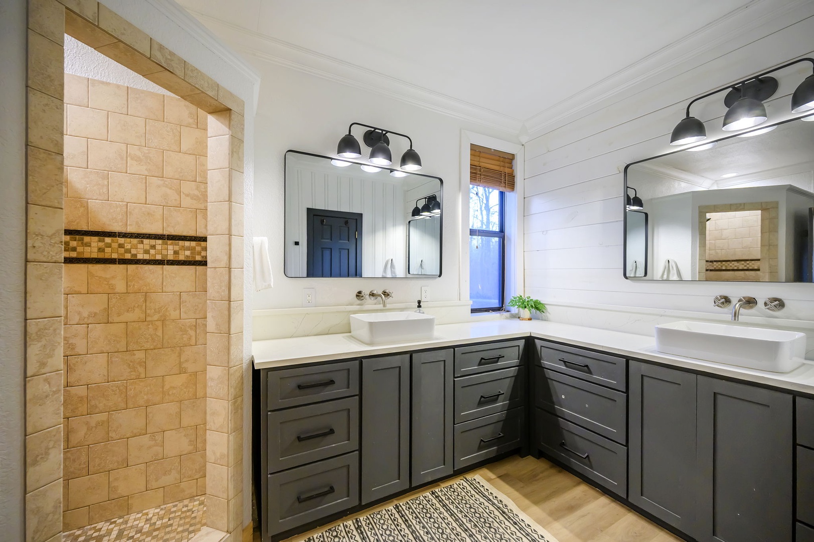 Unwind in your sophisticated master bathroom featuring dual vanities, elegant lighting, and a luxurious stone shower with beautiful tile work.