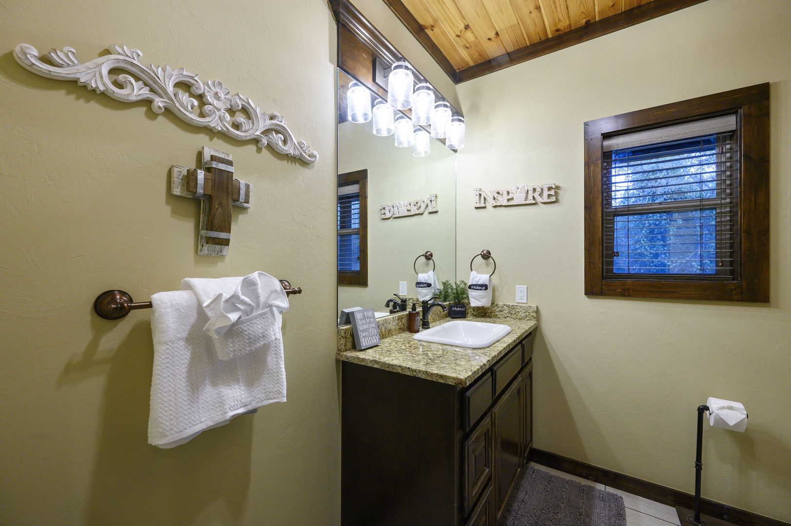 Step into your cozy bathroom featuring a granite-topped vanity, warm wood accents, and fresh towels ready for your arrival. The inviting details and thoughtful touches make it easy to settle in and feel at home.