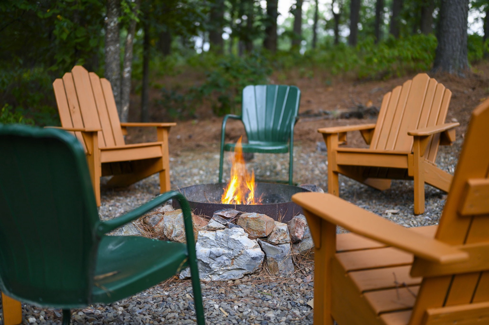 Gather around the crackling fire pit with friends, surrounded by colorful Adirondack chairs and peaceful forest views—your perfect spot for starlit evenings and s'mores.