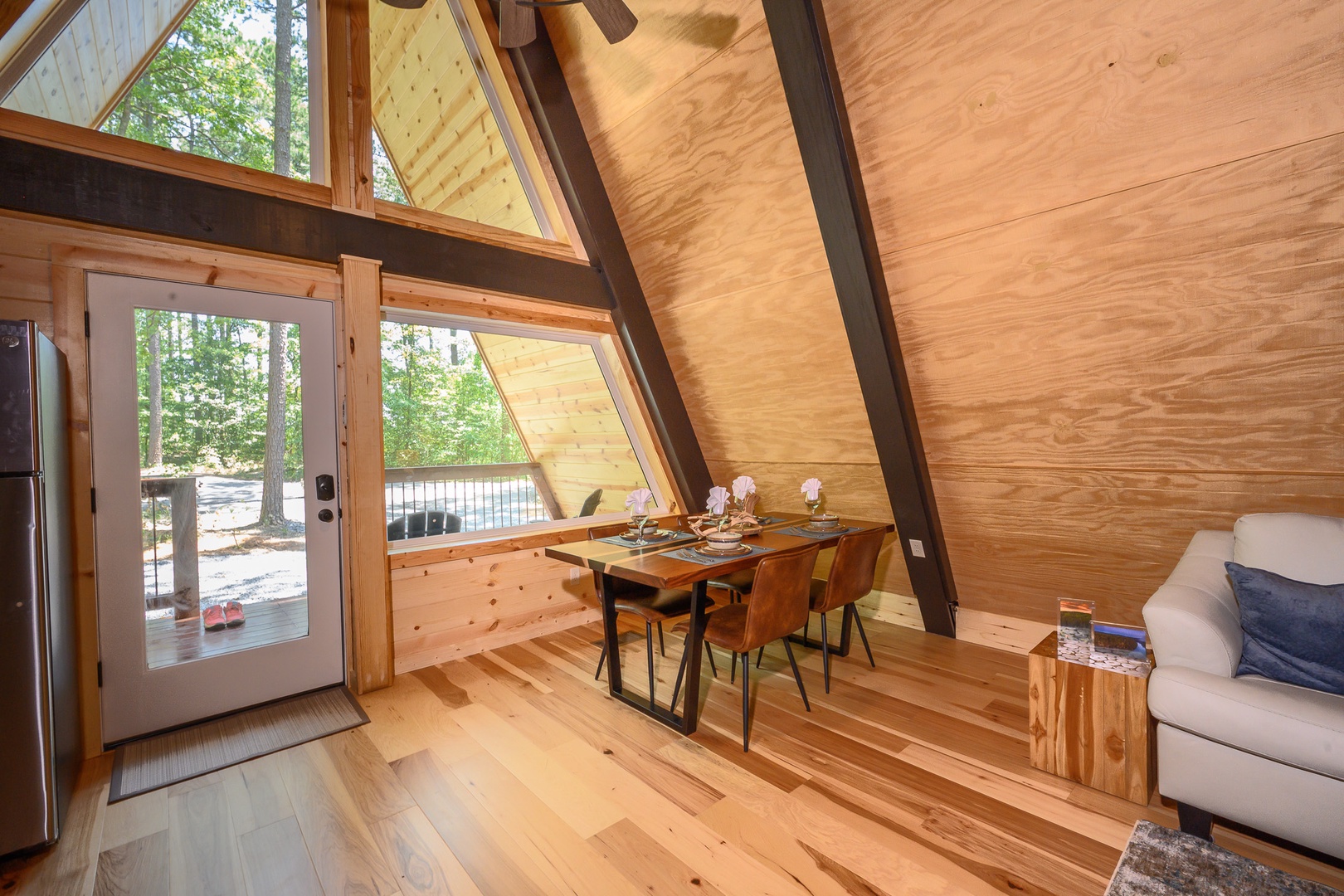 Cozy A-frame retreat with soaring wood ceilings, dramatic windows, and skylights framing the forest. Warm pine walls and gleaming floors create a serene woodland escape.