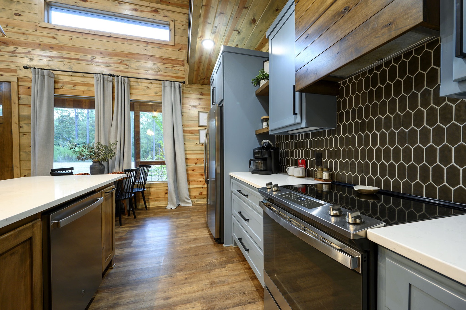 Step into your fully equipped kitchen with striking honeycomb tile backsplash, modern appliances, and warm wood surroundings bathed in natural light—perfect for preparing meals in comfort.
