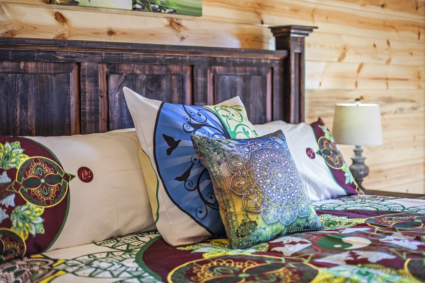 Sink into your cozy cabin bedroom with rustic wood headboard and vibrant bohemian bedding that creates the perfect mountain retreat vibe.
