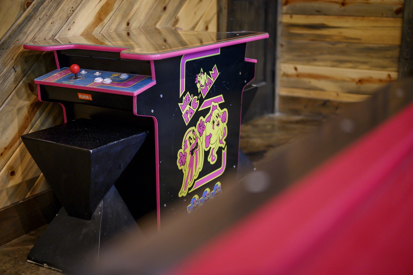 Step back in time with a classic arcade game station set against rustic wood-paneled walls—perfect for friendly competition and nostalgic fun during your stay.