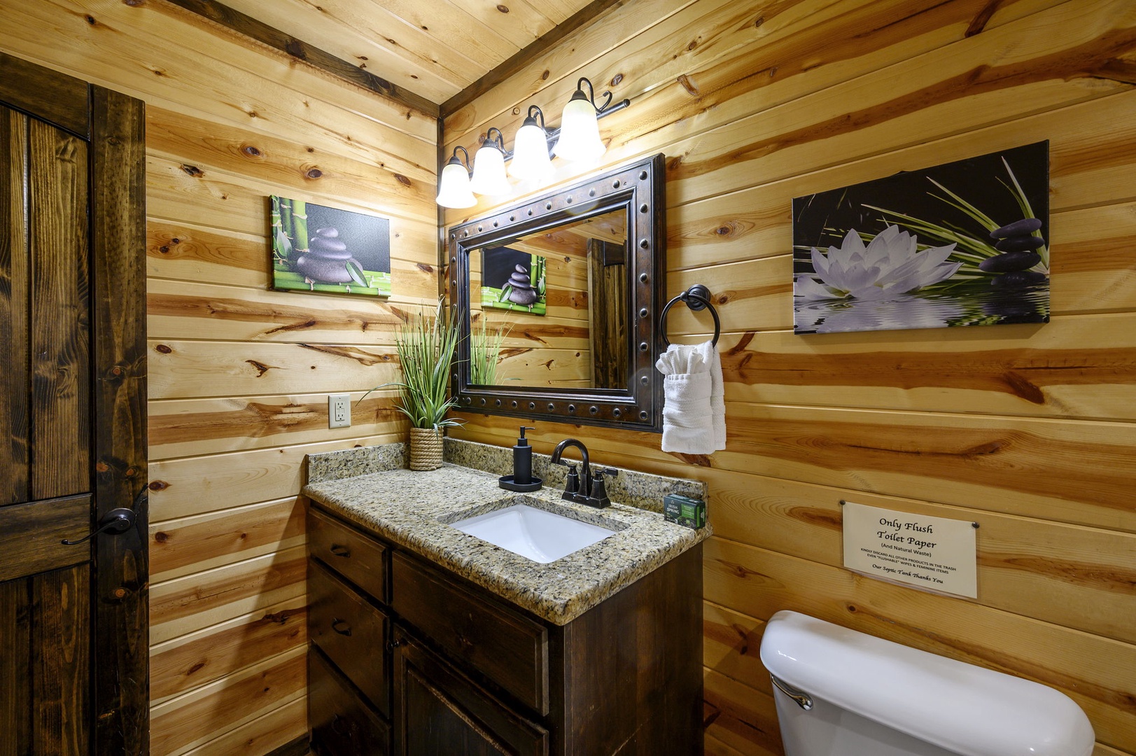 Step into your cozy cabin bathroom, where rustic wood paneling and warm lighting create a peaceful retreat. Refresh at the granite vanity, surrounded by natural touches that invite you to unwind.