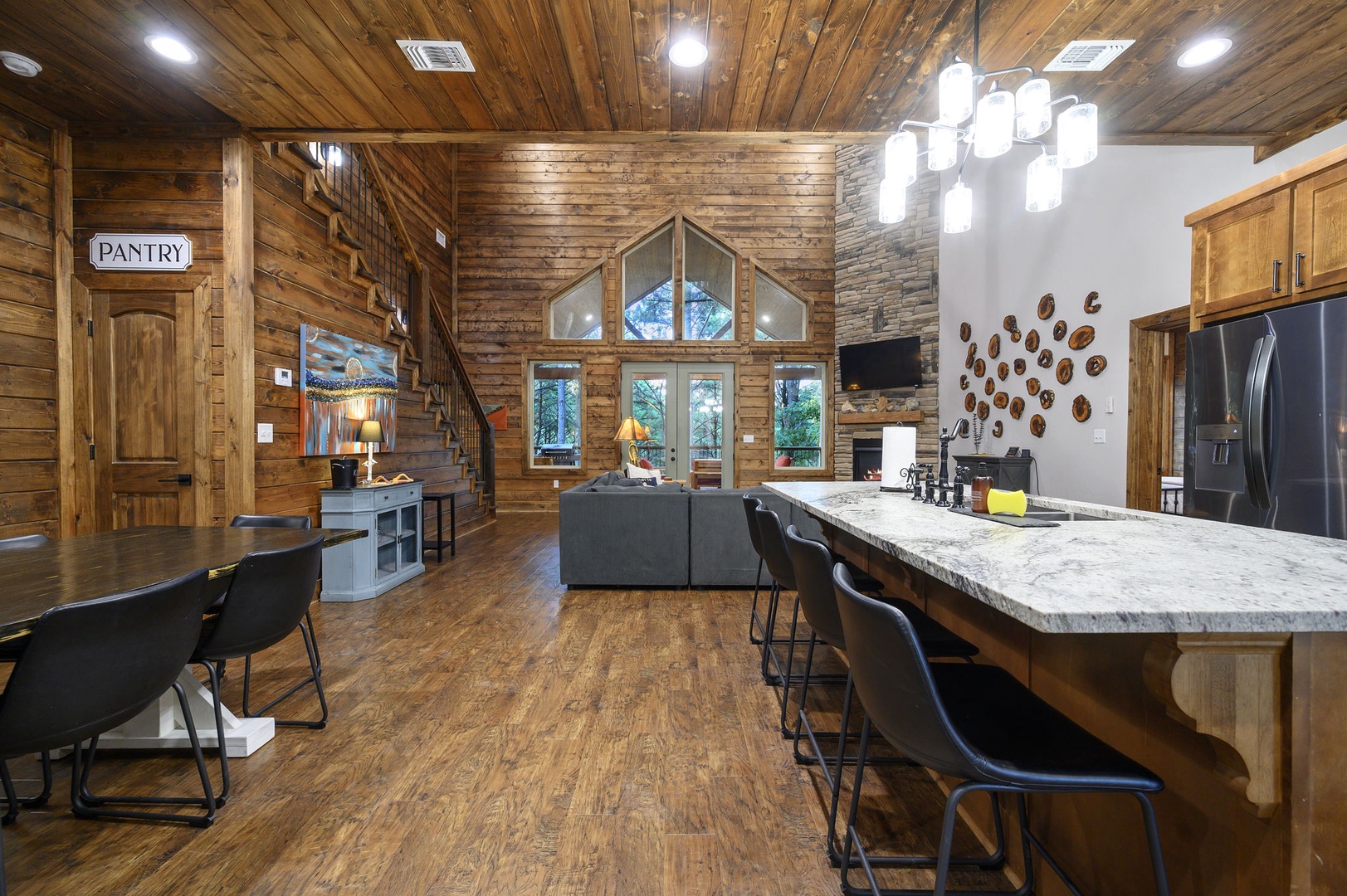 Gather in this stunning open-concept space featuring soaring timber ceilings, an expansive kitchen island with seating for your group, and panoramic windows framing natural light and views.