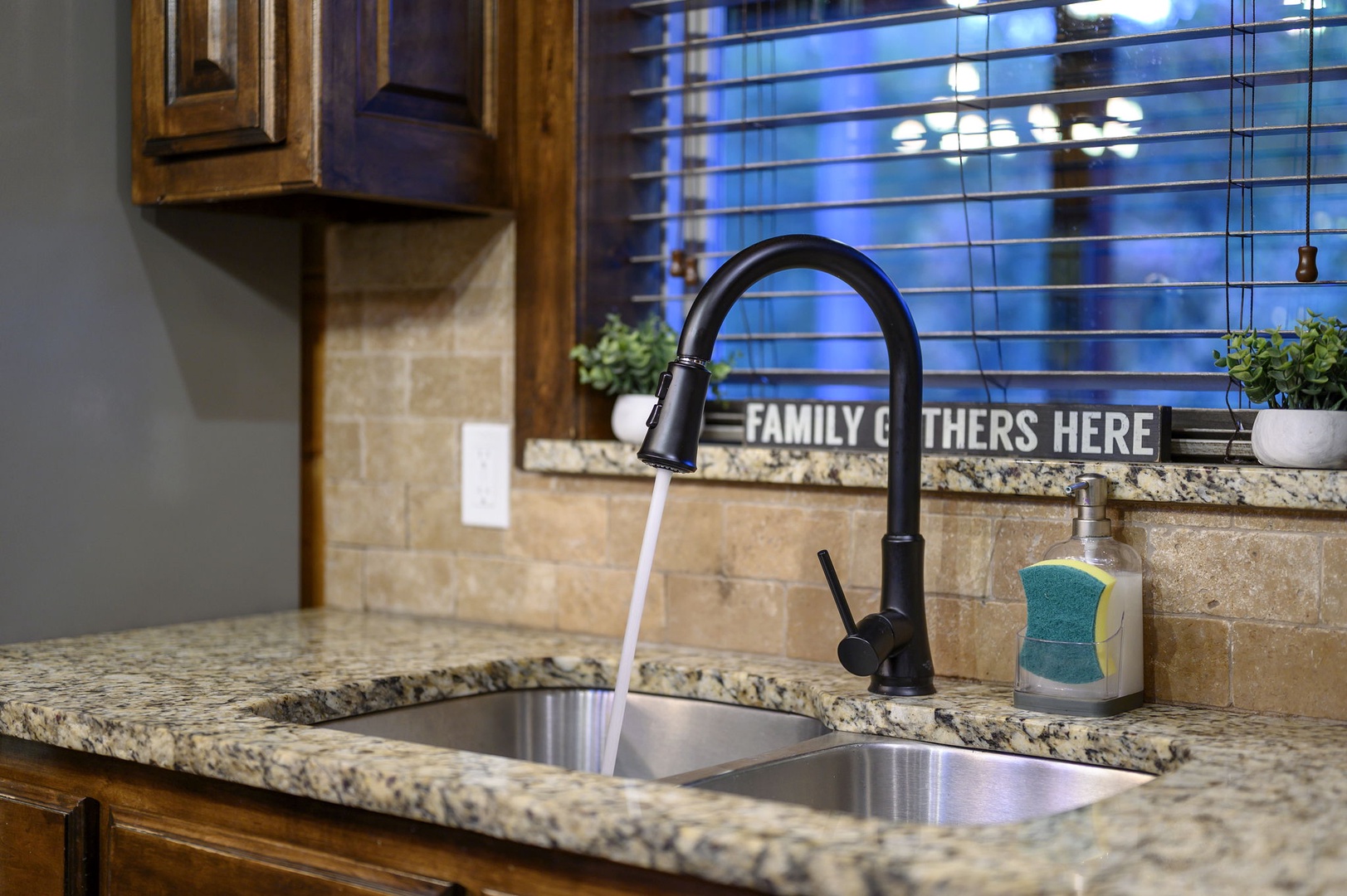 Your fully equipped kitchen features granite counters, a modern faucet, and thoughtful touches like the welcoming sign that reminds you this is a place where family gathers.
