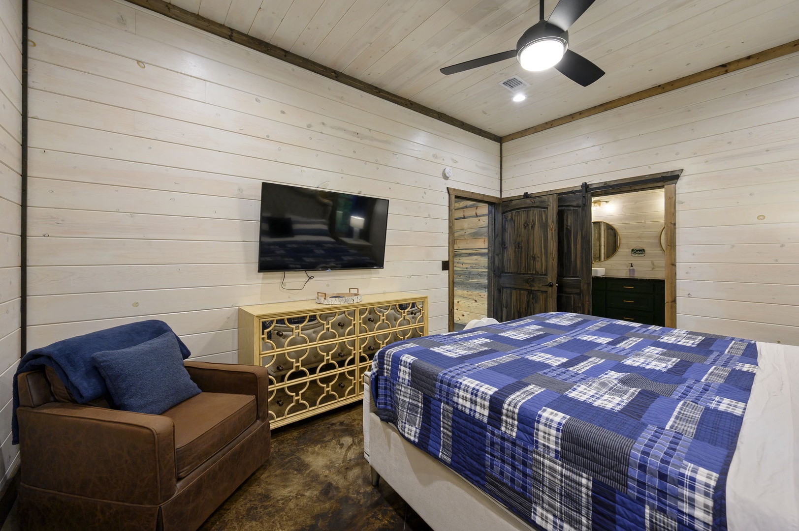 Step into your cozy retreat with modern farmhouse charm. Rustic wood walls, a ceiling fan, and a private en-suite behind the sliding barn door make this bedroom feel like your own peaceful escape.
