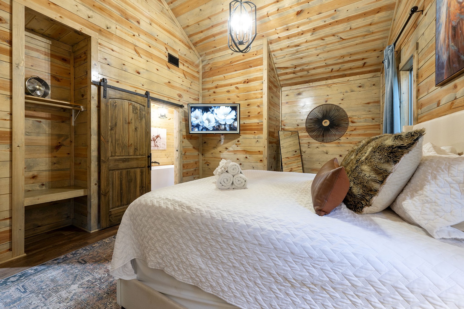 Sink into your cozy bed surrounded by warm pine walls and rustic barn door charm—a peaceful retreat where comfort meets cabin elegance.