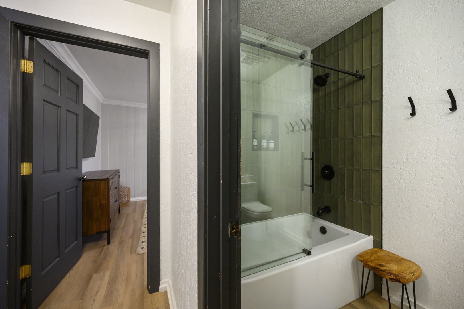 Step into your stylish bathroom featuring a luxurious tub-shower combo with elegant green tile and glass doors for relaxing soaks.