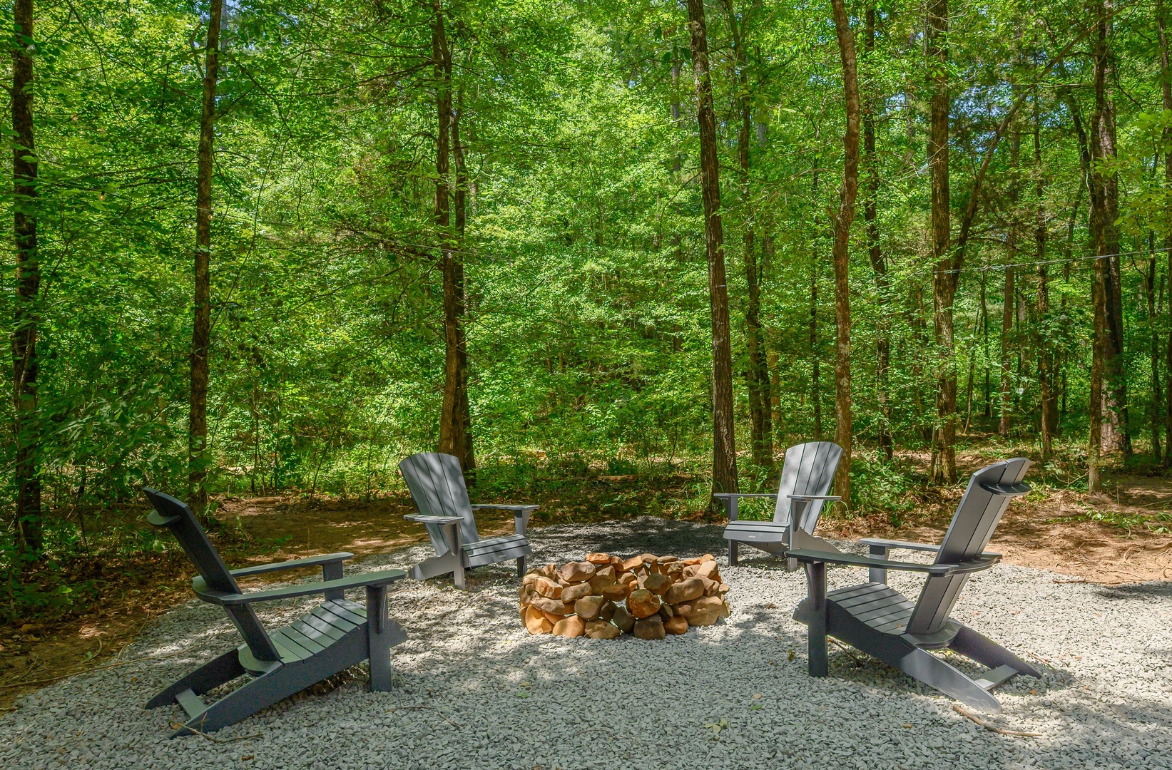 Gather around your private fire pit nestled in the trees. Four Adirondack chairs invite peaceful conversation or quiet moments while nature's canopy frames your retreat.