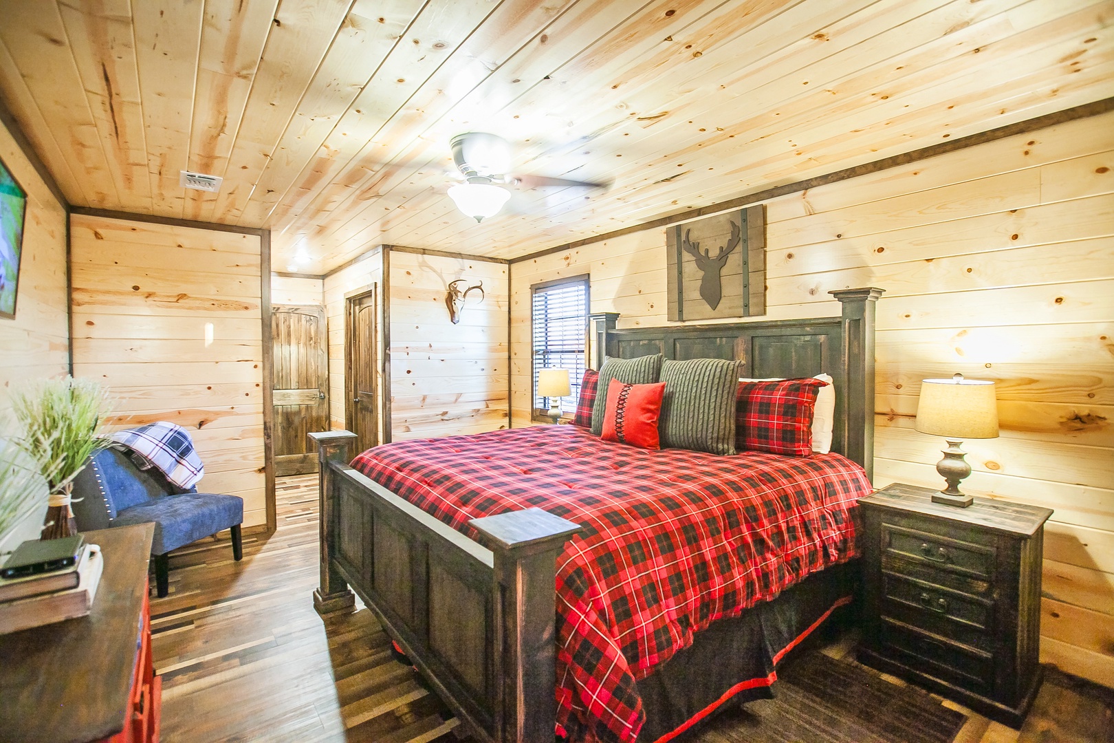 Unwind in your cozy rustic bedroom with warm wood walls, plaid bedding, and charming cabin details that make you feel right at home.
