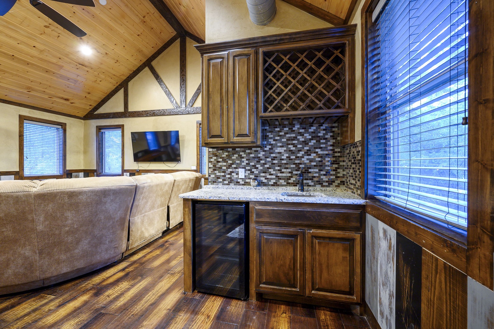 Your cozy cabin retreat features a well-appointed kitchenette with granite countertops, mosaic tile backsplash, and mini fridge—perfect for preparing light meals and storing your favorite beverages during your mountain getaway.
