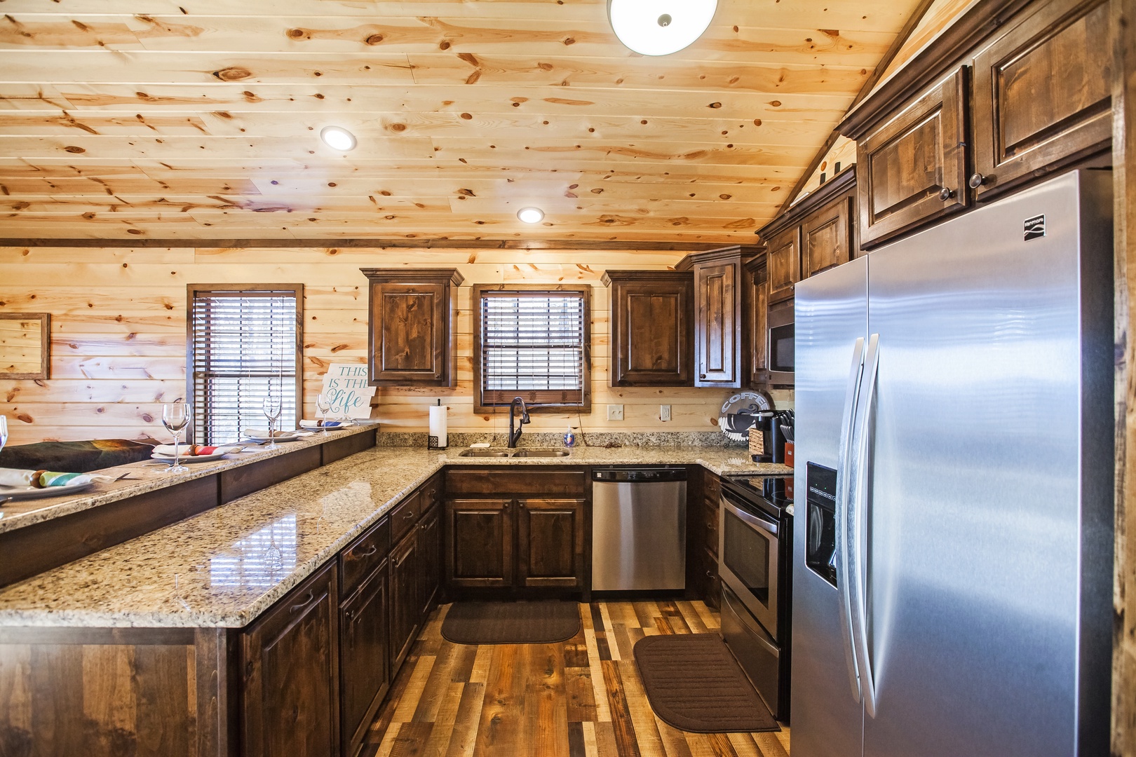 Cook your favorite meals in this fully-equipped kitchen featuring granite countertops, stainless steel appliances, and rustic wood cabinetry.