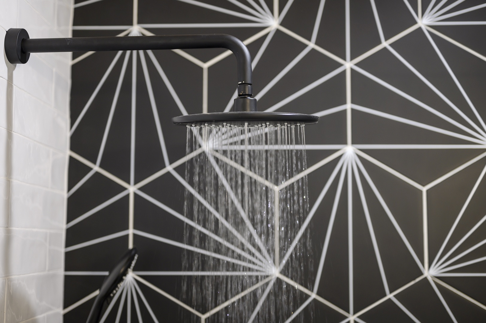 Step into your private rainfall shower featuring striking geometric wallpaper and modern black fixtures for a luxurious daily ritual.