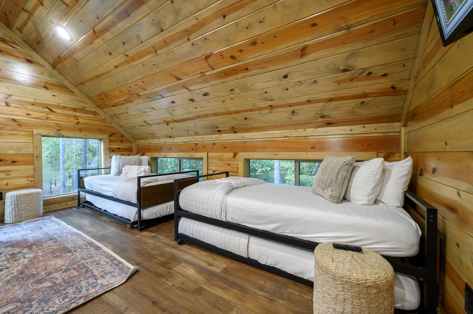 Drift off under soaring wood-paneled ceilings in this bright, airy bedroom with three cozy beds and forest views through large windows.