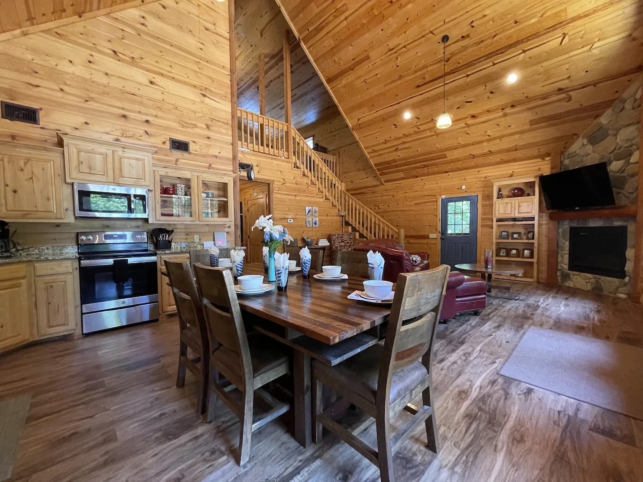 Step into your warm, spacious cabin retreat where pine walls and vaulted ceilings create a cozy mountain atmosphere. Gather around the farmhouse table or relax by the stone fireplace—your perfect home away from home.