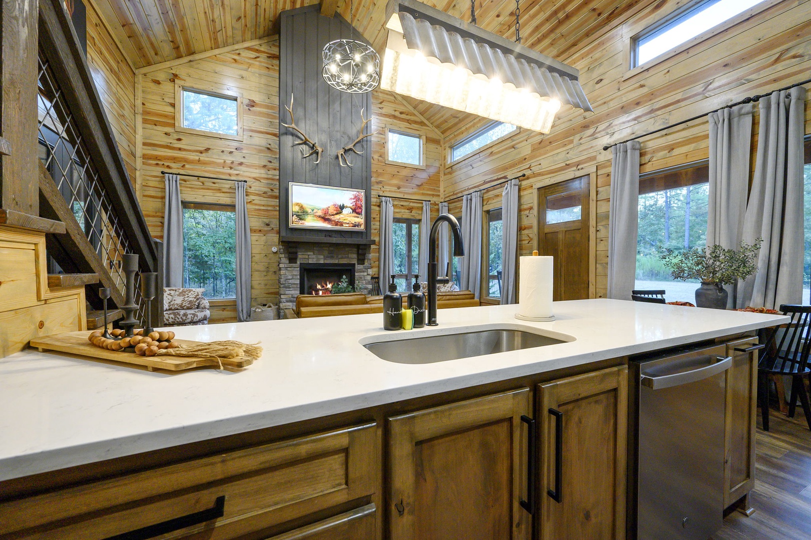 Step into your cozy cabin retreat with vaulted ceilings, warm wood accents, and a stunning stone fireplace. The open kitchen invites you to gather, cook, and unwind while natural light pours through every window.