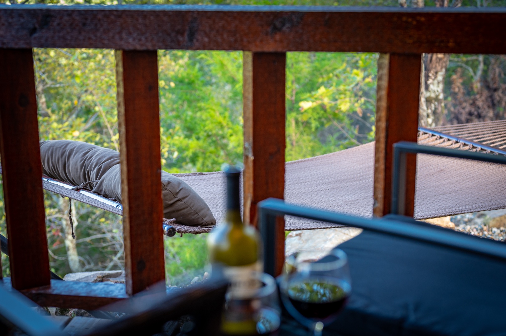 Savor wine moments on your private balcony, where comfortable seating and forest views create the perfect evening retreat.