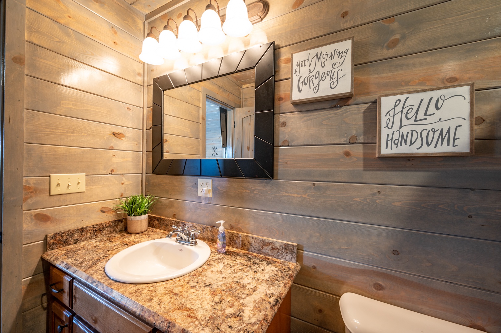 Start your mornings with rustic charm in this welcoming bathroom featuring warm wood walls and cheerful décor touches.