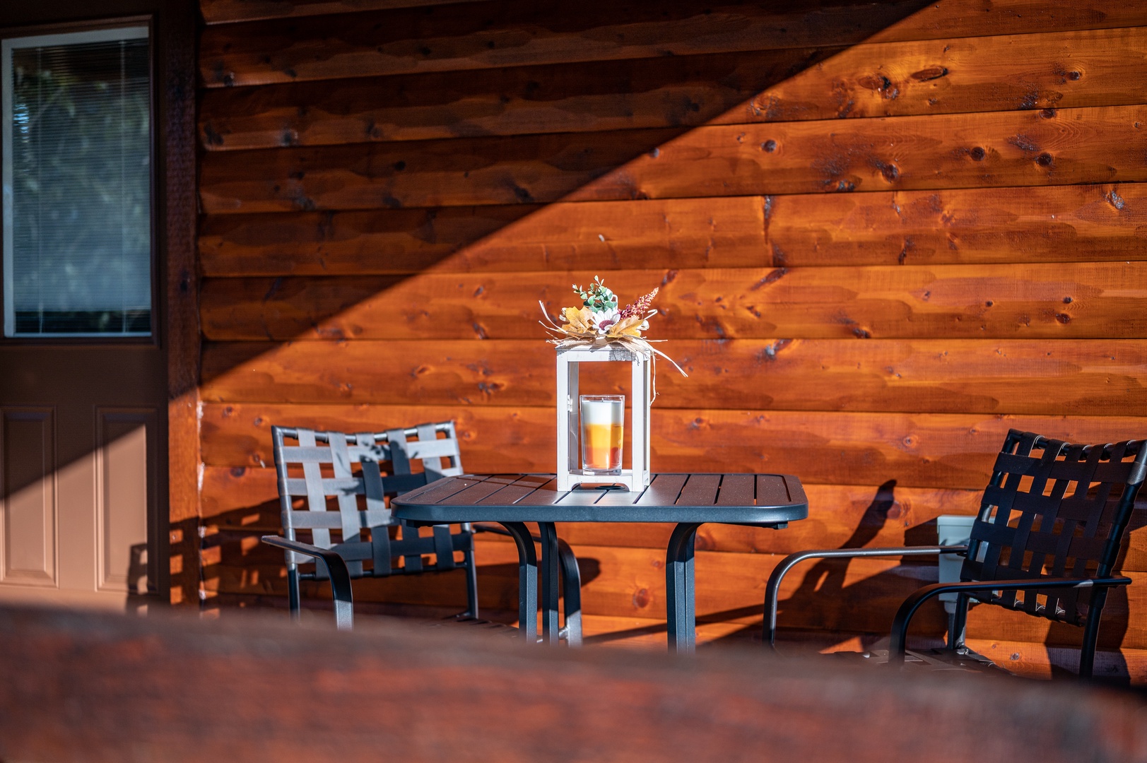 Settle into your private patio's cozy seating area, where warm wood walls create the perfect backdrop for morning coffee or evening relaxation.