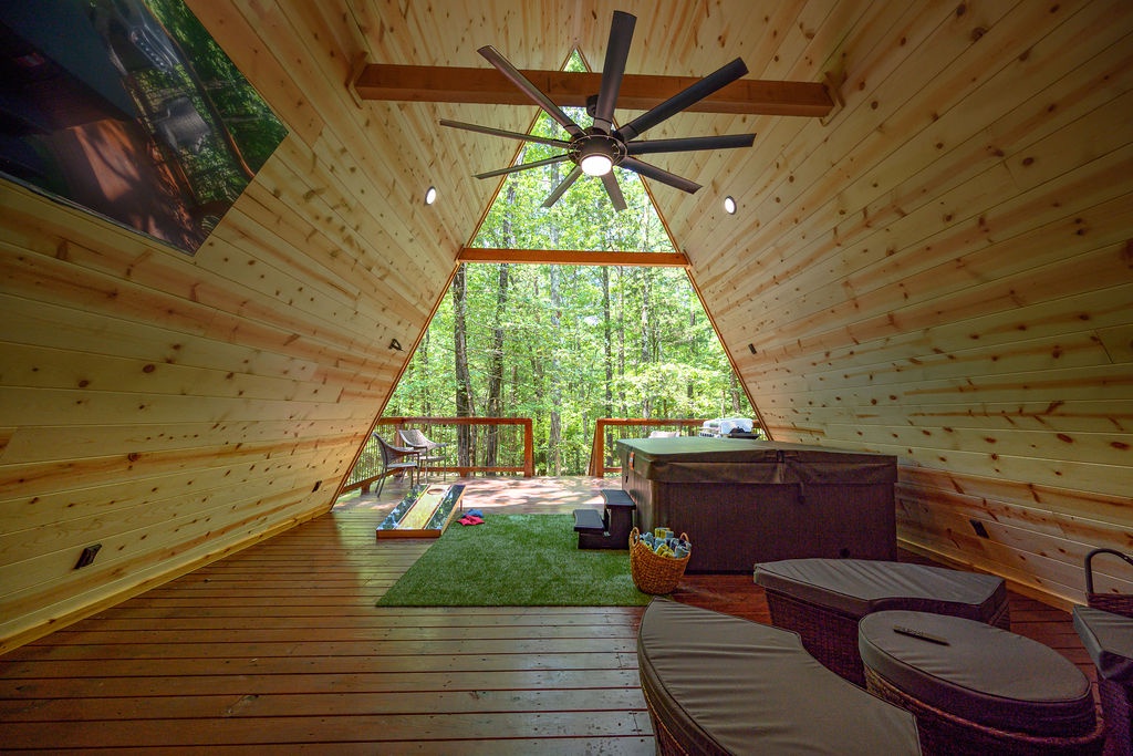 Your private forest retreat features a covered deck with hot tub and modern lounge seating, surrounded by towering trees that bring nature right to your doorstep.