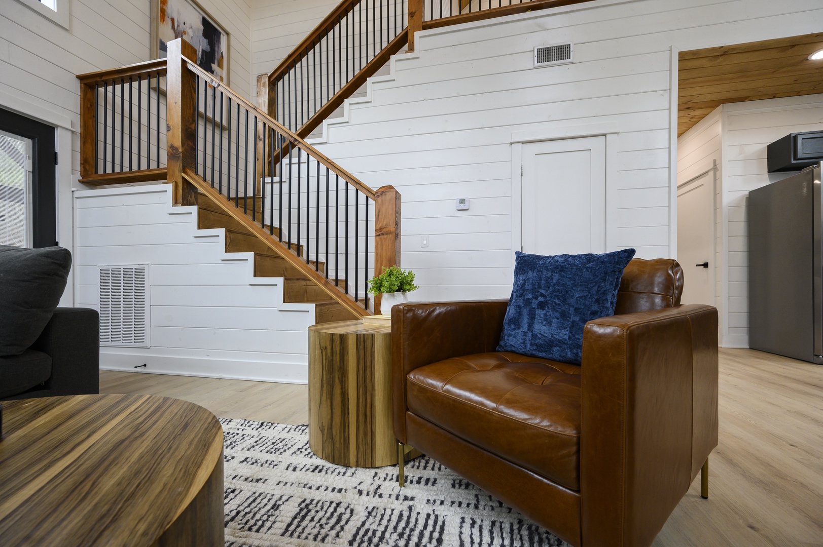 Sink into rich leather seating surrounded by warm wood accents and crisp shiplap walls in this inviting living space.