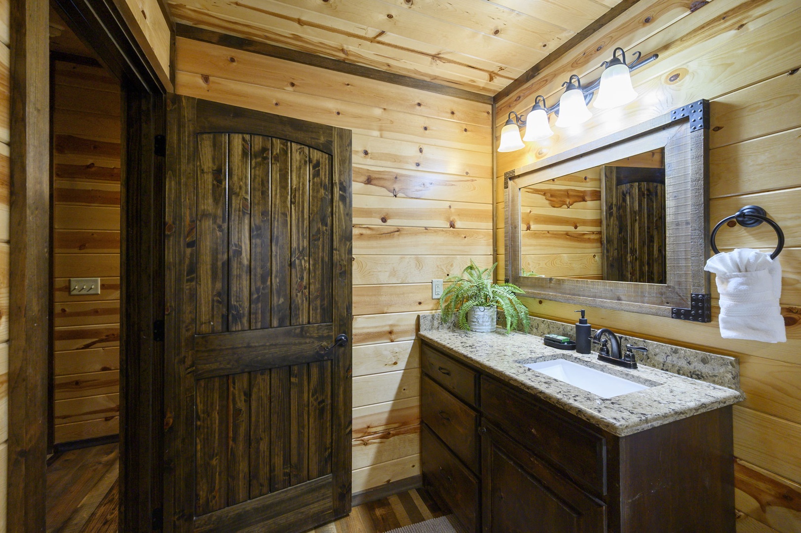 Step into your private bathroom, where warm pine walls and rustic wood accents create a cozy mountain retreat. Granite countertops and soft lighting invite you to unwind after a day of adventure.