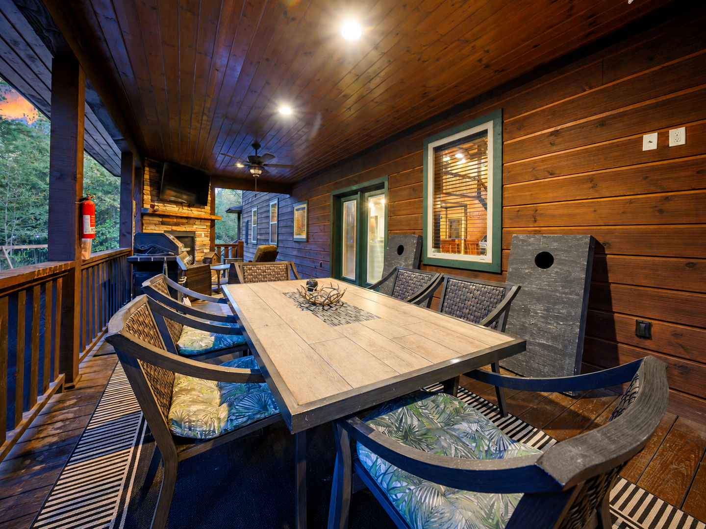 Gather around your private covered deck, where warm wood tones and soft lighting create the perfect setting for memorable meals and conversations under the ceiling fan's gentle breeze.