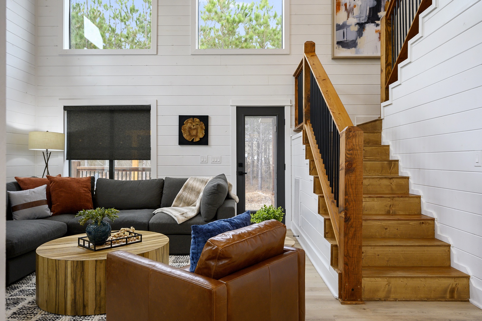 Sink into plush seating where warm leather meets soft fabrics, surrounded by natural light streaming through leafy views.