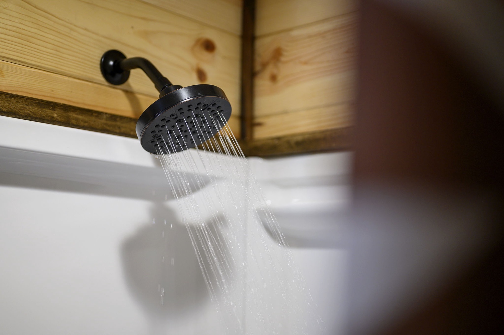 Step into your private rainfall shower, where warm water cascades from a sleek black fixture against natural wood accents, creating a spa-like retreat just for you.