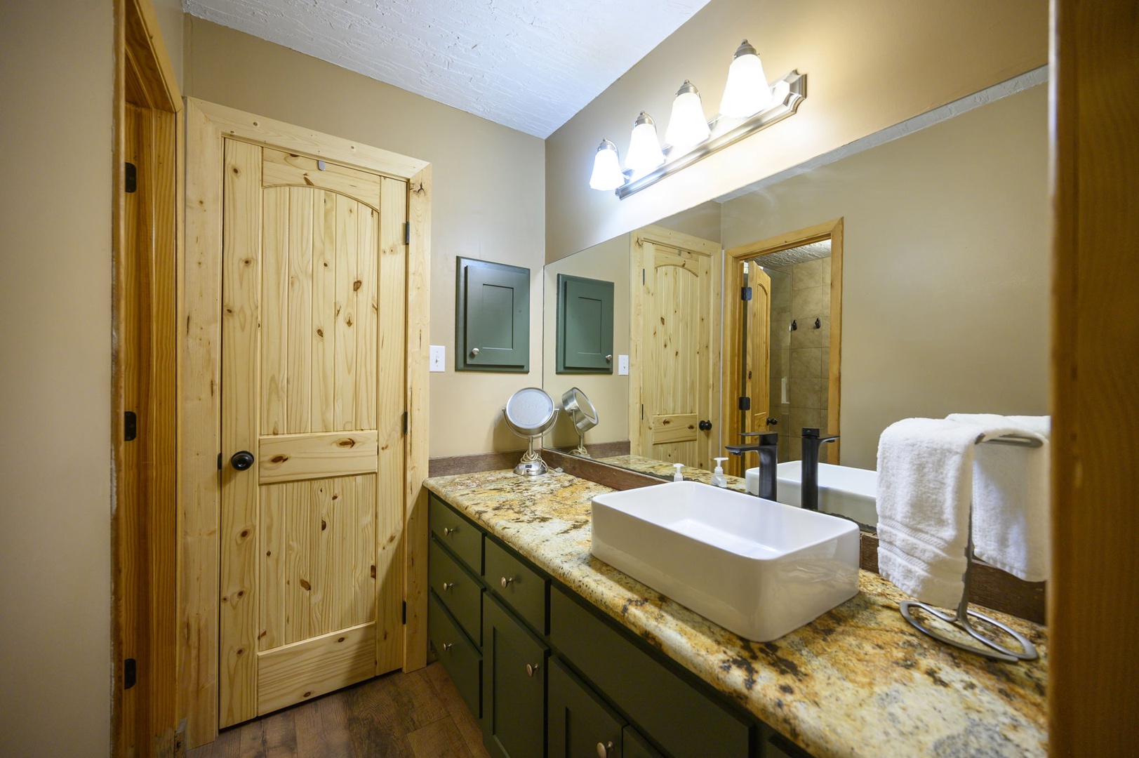 Your private bathroom features granite countertops, a modern vessel sink, and rustic pine doors. Fresh towels await your arrival.