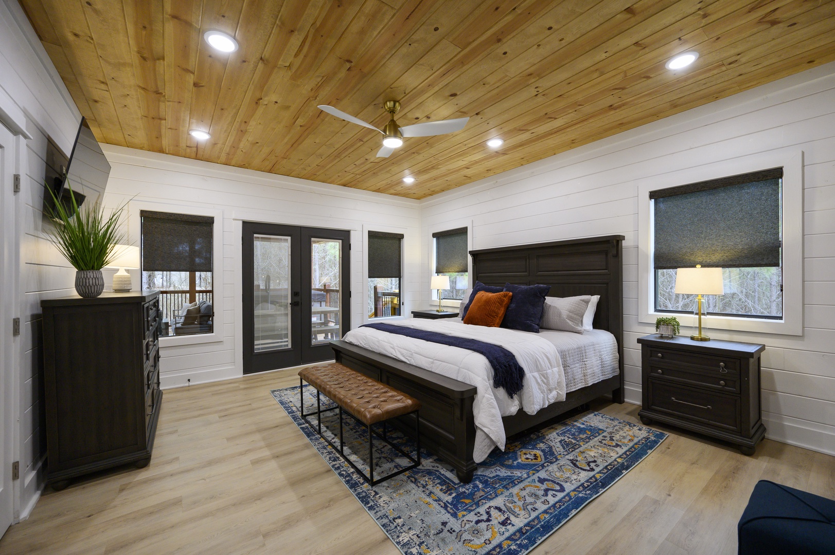 Rest peacefully in your spacious bedroom featuring a stunning wood ceiling, elegant furnishings, and balcony access for morning views.