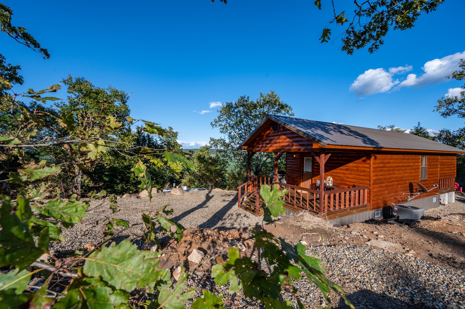 Charming log cabin nestled among vineyards with a welcoming deck and stunning blue sky backdrop.