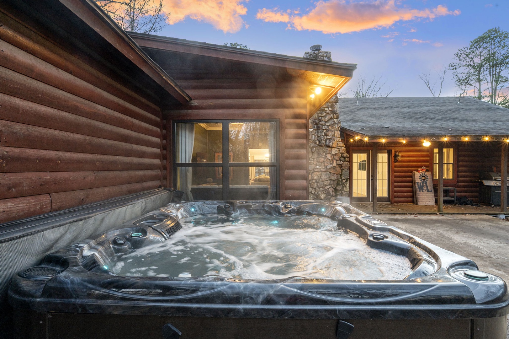 Charming log cabin retreat features a bubbling hot tub where you can unwind under dramatic sunset skies.