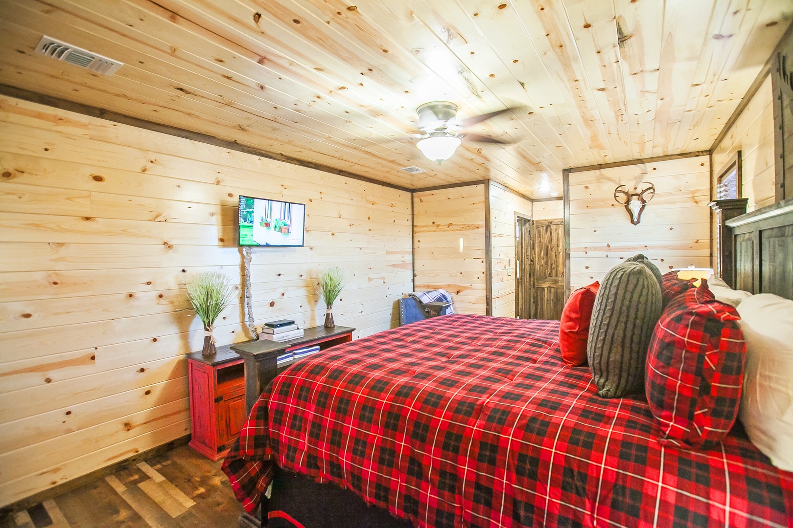 Cozy rustic bedroom with warm wood walls, plaid bedding, and modern amenities for your perfect mountain getaway retreat.
