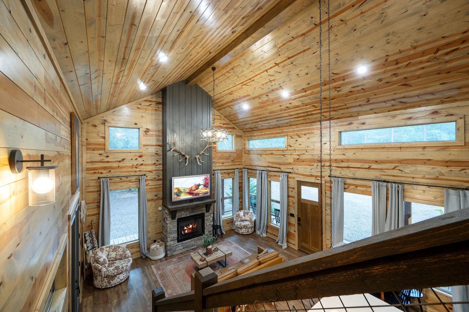 Step into your rustic retreat, where soaring wood-paneled ceilings and abundant natural light create a warm, inviting atmosphere. Curl up by the stone fireplace or unwind in the cozy seating area—your perfect mountain escape awaits.
