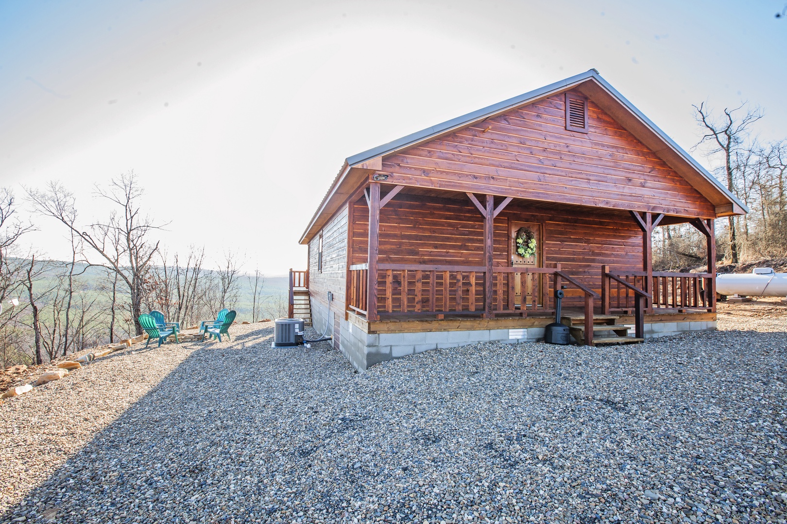 Charming log cabin retreat with covered porch and mountain views, surrounded by peaceful wooded landscape.