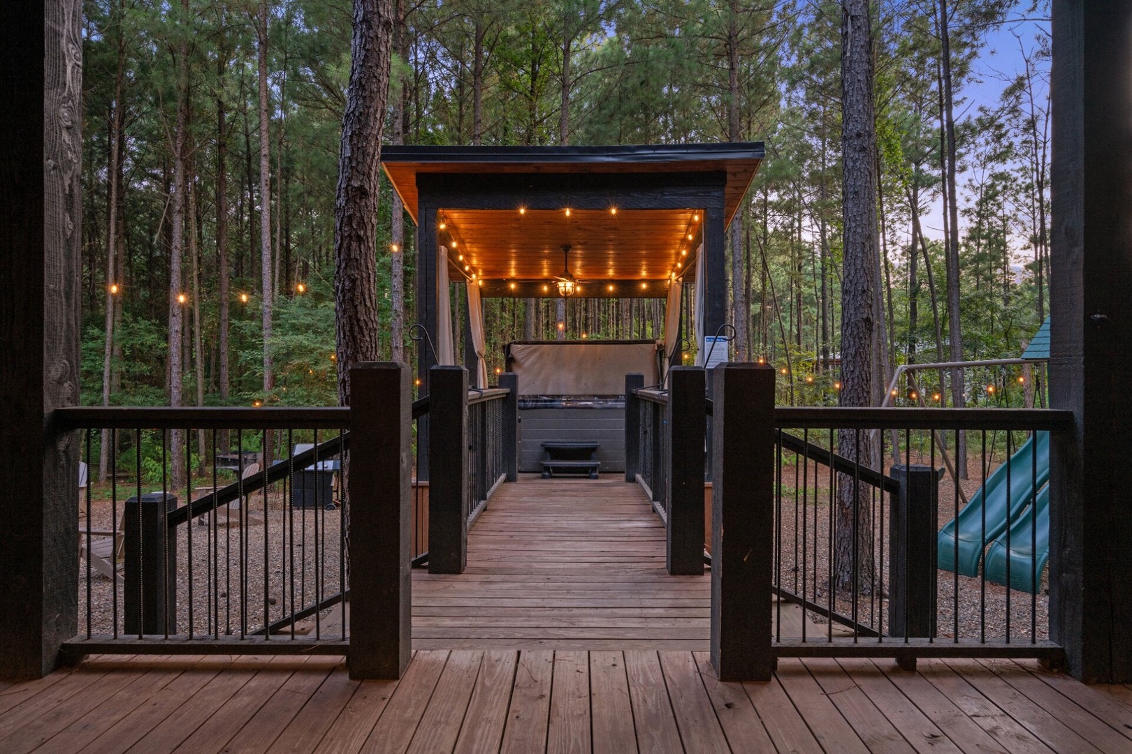 Step onto your private deck and into a peaceful forest retreat, where string lights glow above your personal hot tub and BBQ pavilion—perfect for unwinding under the trees after a long day of exploring.