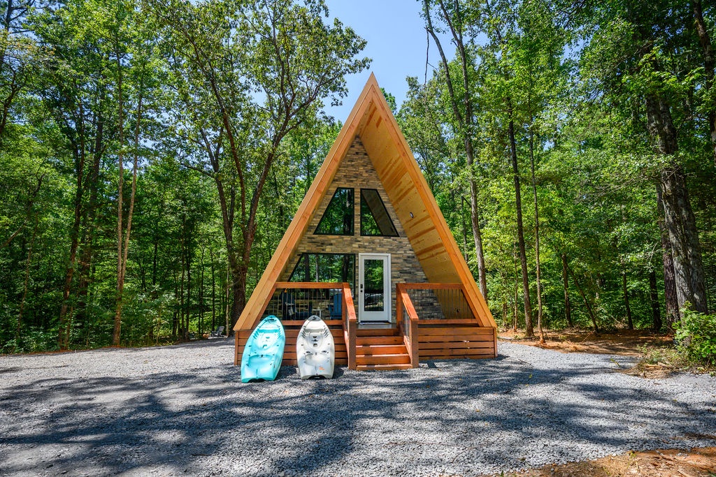 A charming A-frame cabin tucked into a peaceful forest setting, surrounded by towering trees and natural beauty for a secluded retreat.