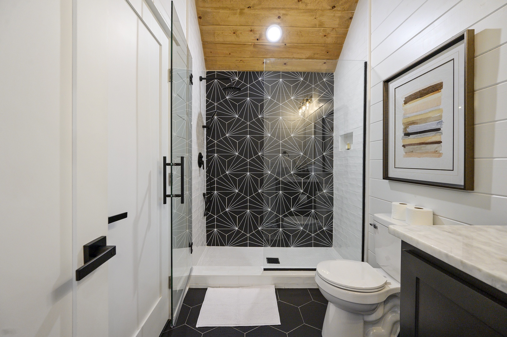 Step into your spa-like retreat with geometric tile shower, warm wood ceiling, and sophisticated black-white design—pure luxury awaits.