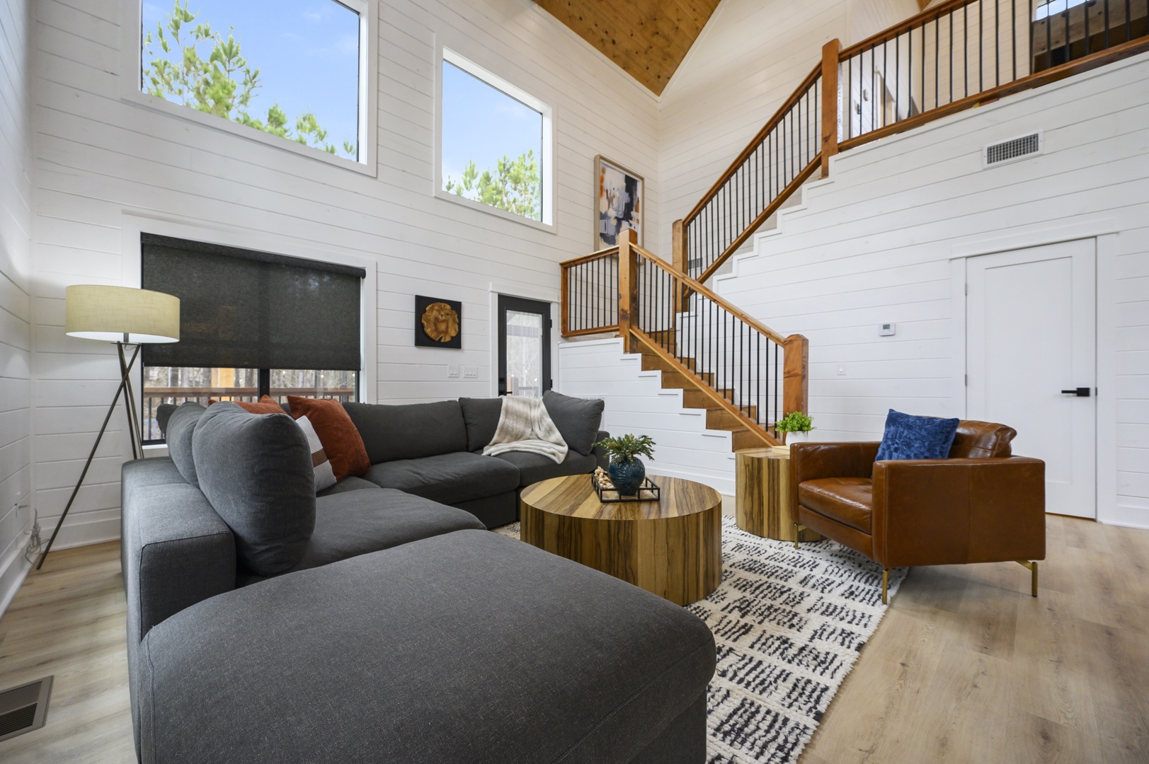 Step into your bright, airy living space with soaring ceilings, cozy seating, and warm wood accents that create the perfect retreat.