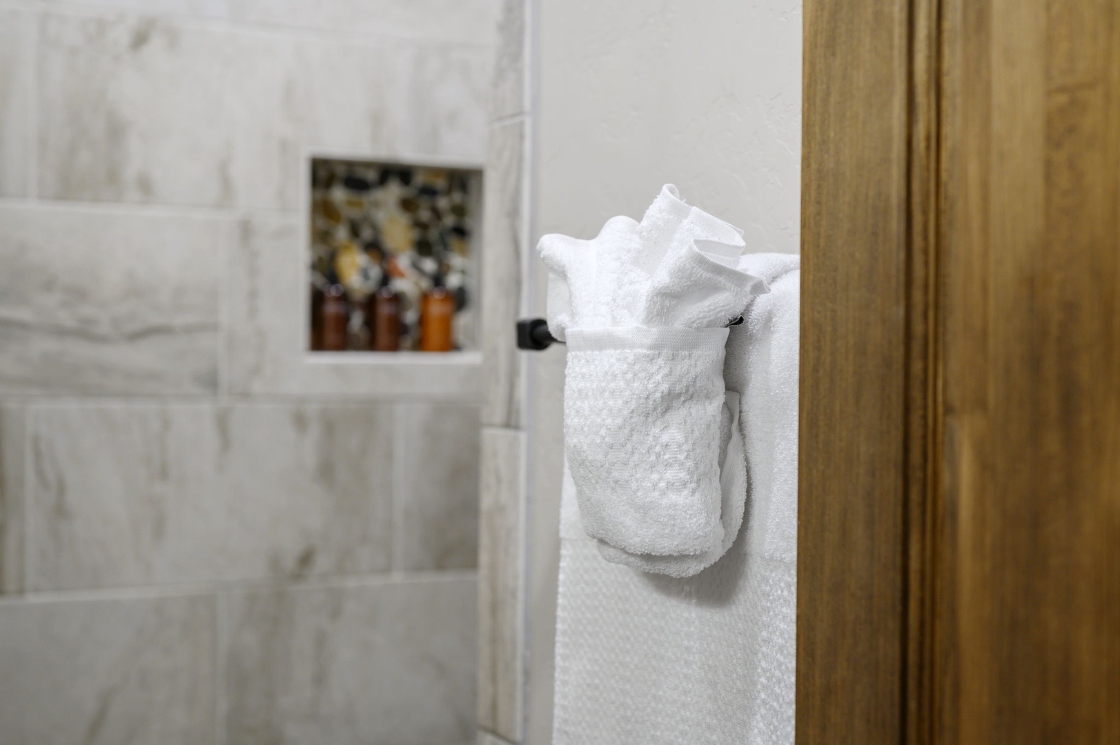 Plush white towels await you after your refreshing shower, with premium toiletries ready in the marble-tiled enclosure.