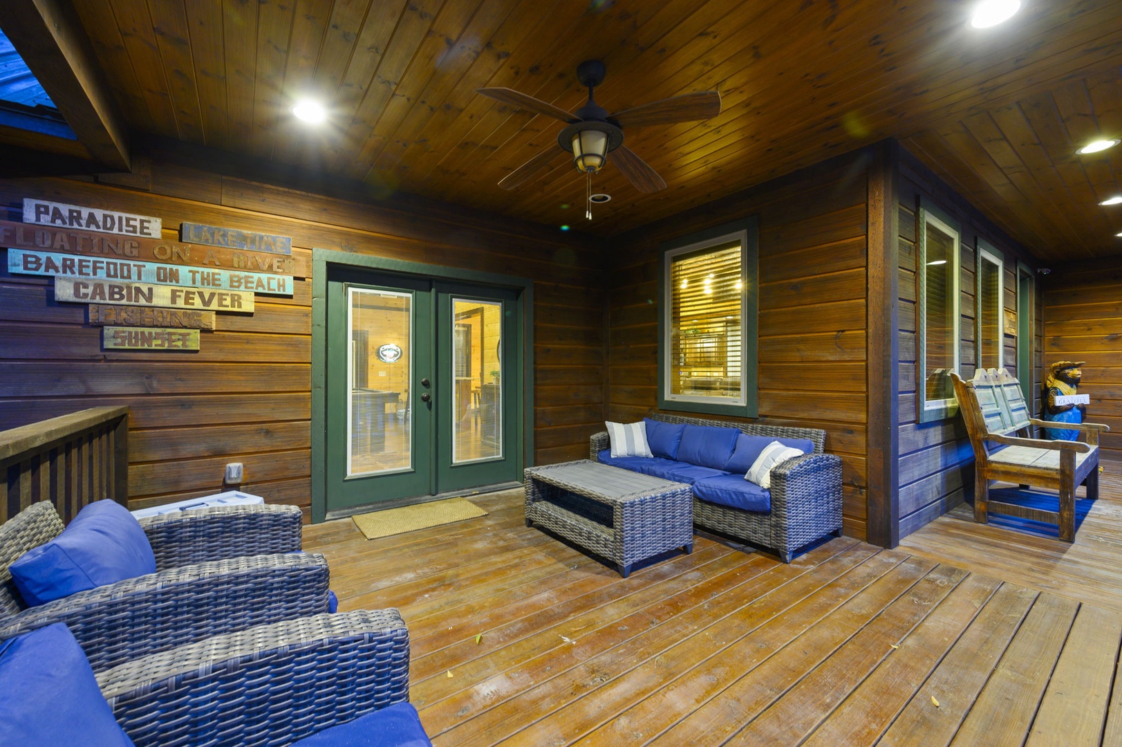 Sink into plush wicker seating on your private covered porch, where warm wood tones and playful beach signs create the perfect spot to unwind after a day of adventure.