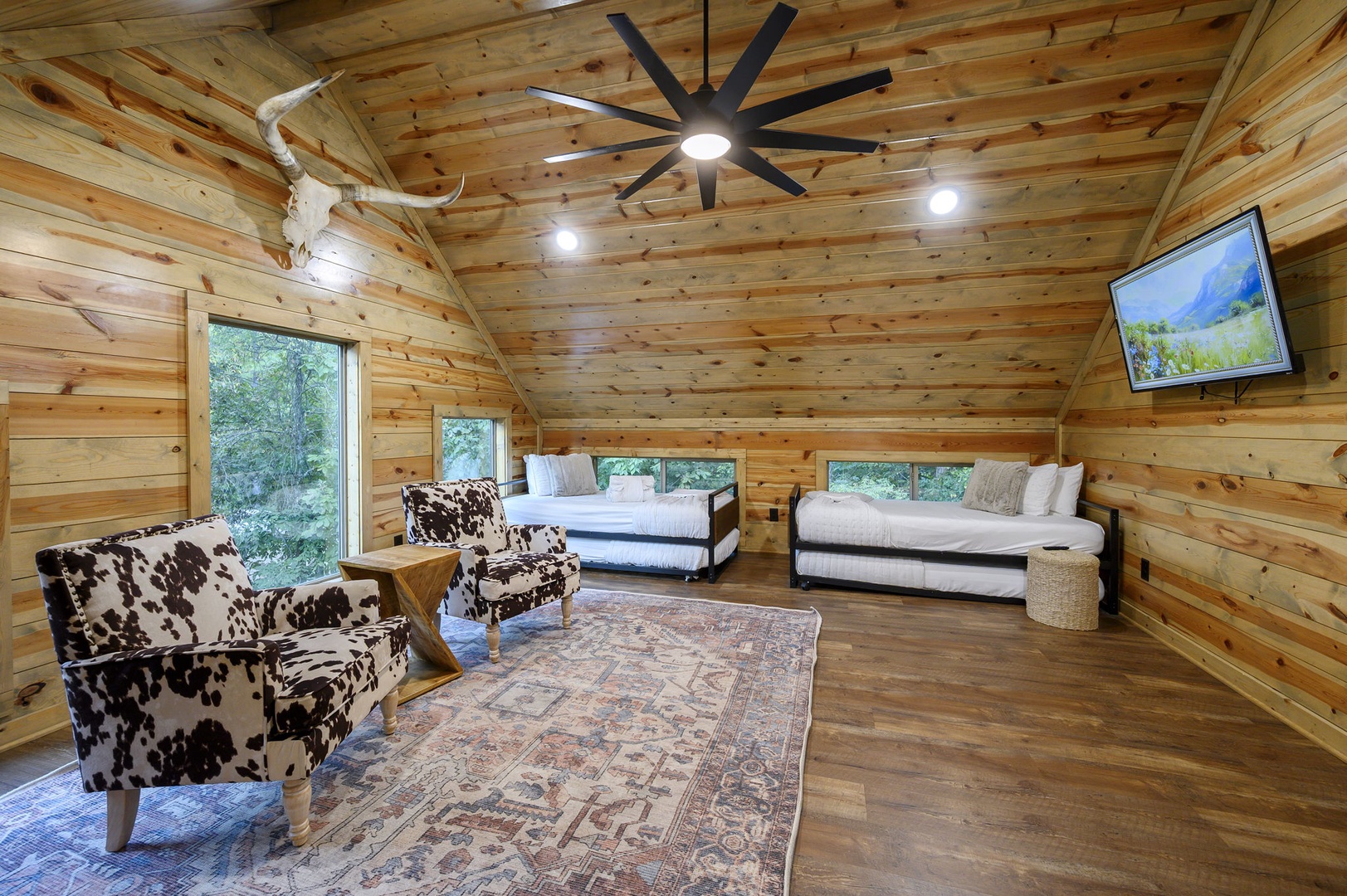 Curl up in your own cozy cabin retreat, where warm wood surrounds you and two inviting beds promise restful nights beneath the rustic ceiling fan.
