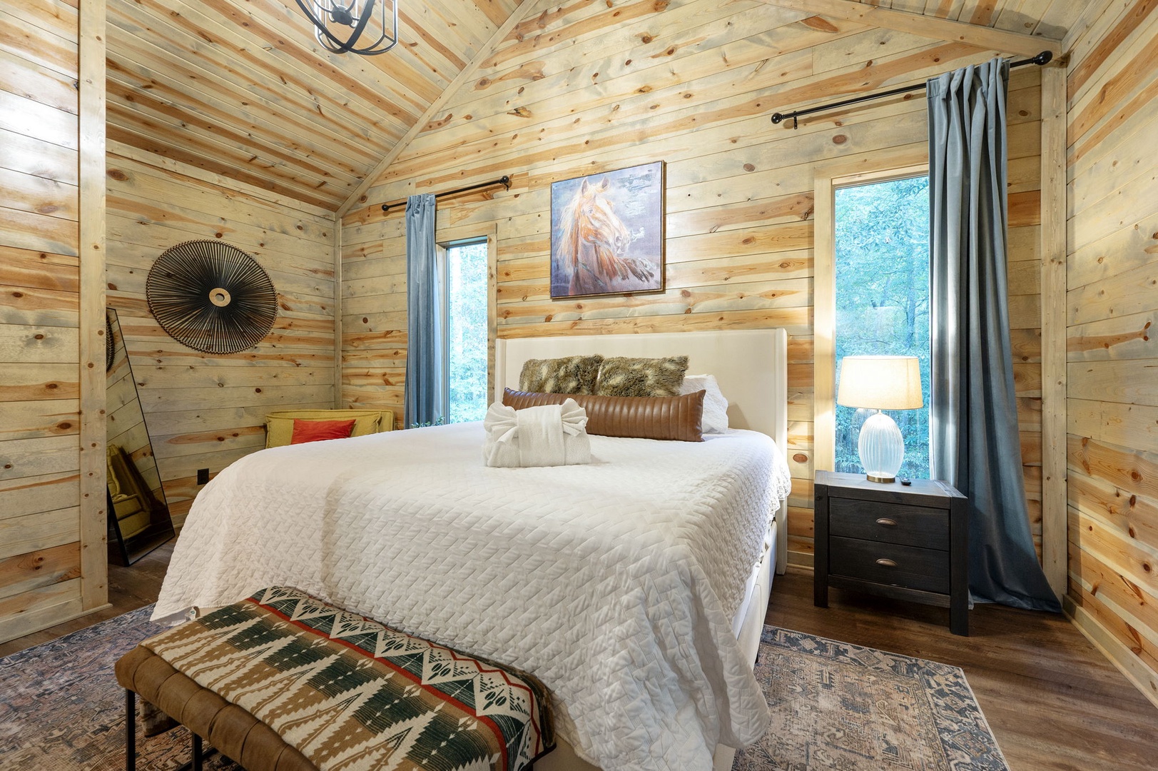 Unwind in your private bedroom retreat, where rustic wood-paneled walls meet modern comfort. Drift off under vaulted ceilings with soft linens and peaceful forest views just outside your windows.