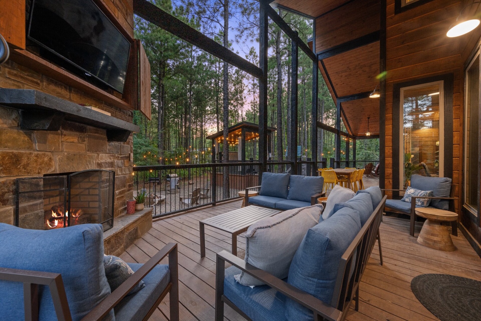 This peaceful woodland retreat features towering pines framing your private porch, where cozy seating and a glowing fireplace invite you to unwind with the forest as your backdrop.